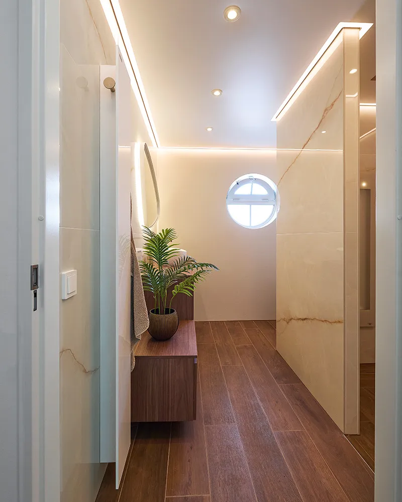 Badkamer in Groenlo met wastafelmeubel in warm walnoot en lichte marmerlook tegels.